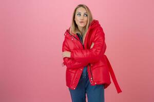 blond happy attractive active woman posing on pink background in colorful winter down jacket of red color, having fun, warm coat fashion trend, smiling photo
