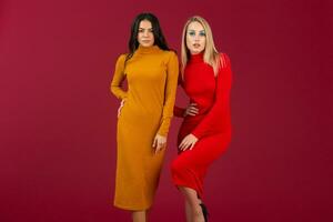 pretty stylish women in yellow and red autumn winter fashion knitted dress posing isolated on red studio background photo