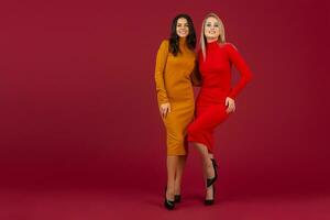 hermosa elegante mujer amigos en amarillo y rojo otoño invierno Moda de punto vestir posando aislado en rojo estudio antecedentes foto