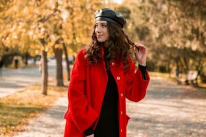 atractivo elegante mujer caminando en parque vestido en calentar rojo Saco foto