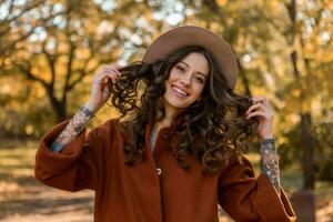 attractive stylish woman walking in park dressed in warm brown coat photo