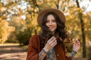 attractive stylish woman walking in park dressed in warm brown coat photo