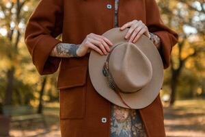 attractive stylish woman walking in park dressed in warm brown coat photo