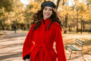 attractive stylish woman walking in park dressed in warm red coat photo