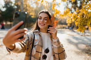 attractive young woman walking in autumn wearing jacket using phone photo