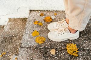 close-up view on stylish beige shoes of young woman walking in autumn park with wearing trousers in fashion style trend photo