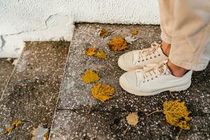 close-up view on stylish beige shoes of young woman walking in autumn park with wearing trousers in fashion style trend photo