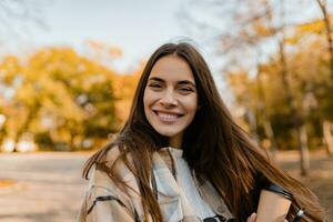 atractivo joven mujer caminando en otoño vistiendo chaqueta foto