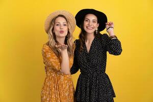 beautiful women friends together isolated on yellow background in black and yellow dress and hat photo