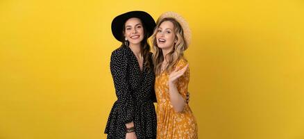 beautiful women friends together isolated on yellow background in black and yellow dress and hat photo