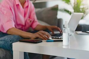 close up focus of spray sanitizer antiseptic at workplace at home working online on laptop photo