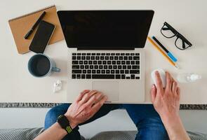 flat lay view from above on table workplace close-up man hands at home working typing on laptop photo