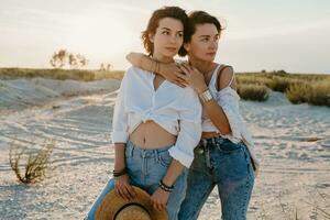 dos joven mujer teniendo divertido en el puesta de sol playa foto