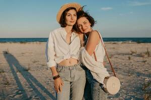 dos joven mujer teniendo divertido en el puesta de sol playa foto