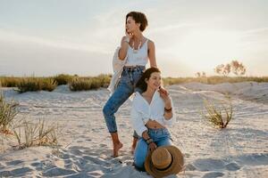 two young women having fun on the sunset beach photo