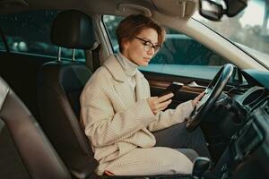 attractive stylish woman sitting in car dressed in coat photo