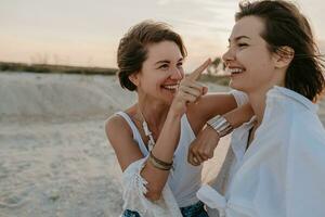 dos joven mujer teniendo divertido en el puesta de sol playa foto