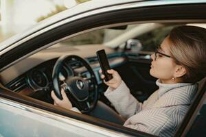 attractive stylish woman sitting in car dressed in coat photo