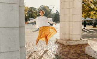 young pretty happy smiling woman in yellow printed dress and knitted white sweater photo