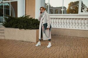 stylish fashionable woman walking in street in elegant style coat photo