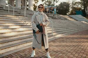 stylish fashionable woman walking in street in elegant style coat photo