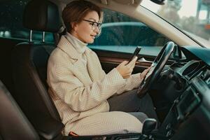 attractive stylish woman sitting in car dressed in coat photo