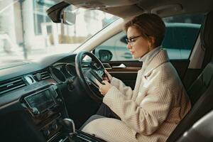 attractive stylish woman sitting in car dressed in coat photo