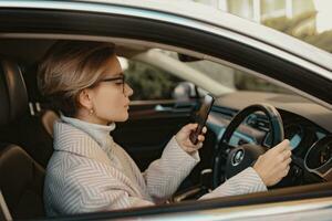 attractive stylish woman sitting in car dressed in coat photo