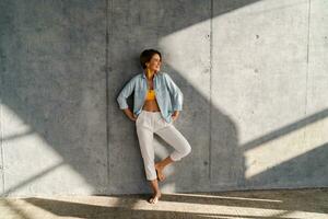 smiling happy beautiful woman posing against concrete wall on sunny day summer fashion style trend photo