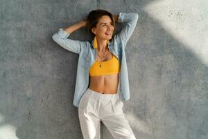 smiling happy beautiful woman posing against concrete wall on sunny day summer fashion style trend photo