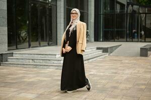 modern stylish muslim woman in hijab in city street photo