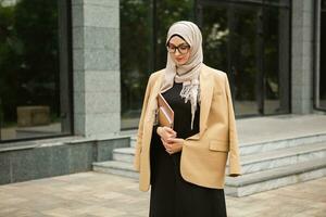 moderno elegante musulmán mujer en hijab en ciudad calle foto