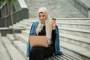 modern stylish muslim woman in hijab in city street photo