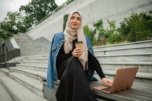 modern stylish muslim woman in hijab in city street photo