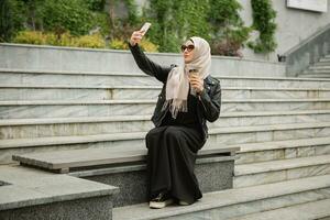 modern stylish muslim woman in hijab in city street photo