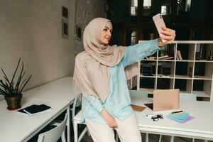 modern muslim woman in hijab in office room photo