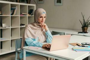 musulmán mujer en hijab trabajando en oficina habitación foto