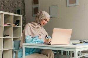 musulmán mujer en hijab trabajando en oficina habitación foto