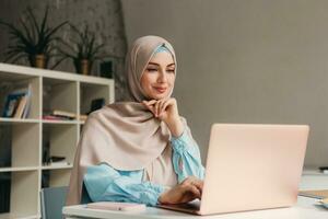 modern muslim woman in hijab in office room photo