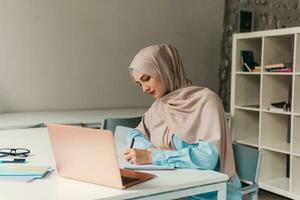 moderno musulmán mujer en hijab en oficina habitación foto