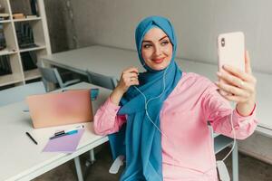 musulmán mujer en hijab trabajando en oficina habitación foto