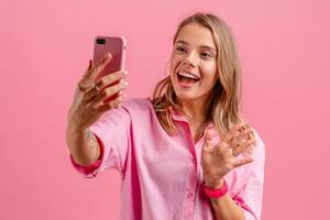 rubio bonito mujer en rosado camisa sonriente participación participación utilizando teléfono inteligente foto