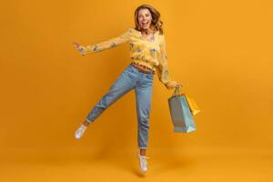 beautiful attractive smiling woman in yellow shirt and jeans with shopping bags photo