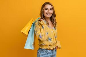 hermosa atractivo sonriente mujer en amarillo camisa y pantalones participación compras pantalones foto