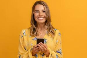 beautiful attractive smiling woman in yellow shirt holding smartphone photo