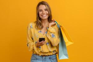 hermosa atractivo sonriente mujer en amarillo camisa y pantalones participación compras pantalones foto