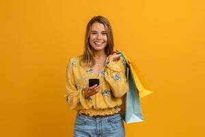 beautiful attractive smiling woman in yellow shirt and jeans holding shopping bags photo