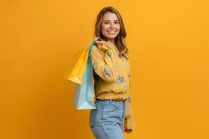 hermosa atractivo sonriente mujer en amarillo camisa y pantalones participación compras pantalones foto