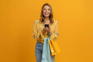 beautiful attractive smiling woman in yellow shirt and jeans holding shopping bags photo