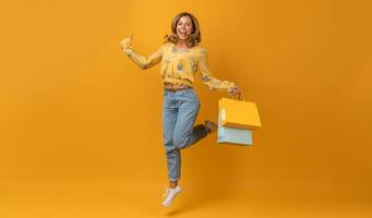 beautiful attractive smiling woman in yellow shirt and jeans with shopping bags photo